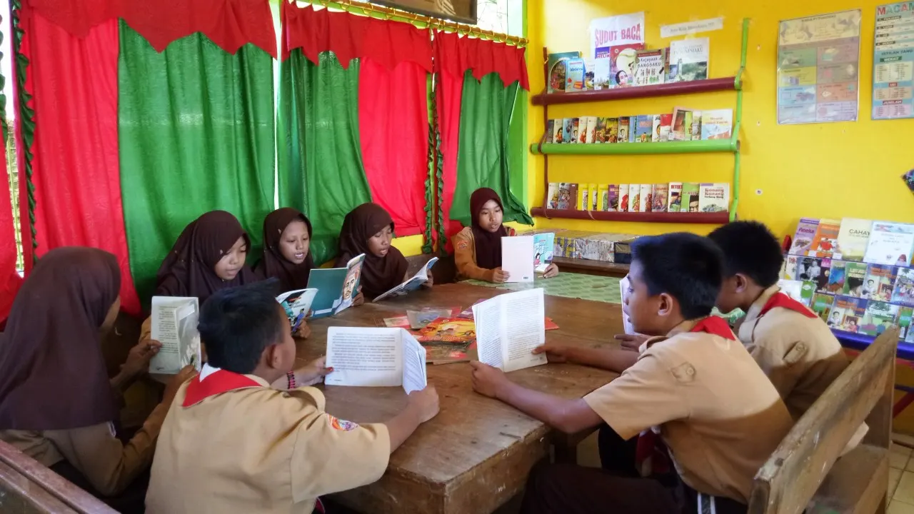 Siswa SMP di Indonesia sedang membaca buku bersama di sudut baca kelas sebelum pembelajaran Bahasa Indonesia