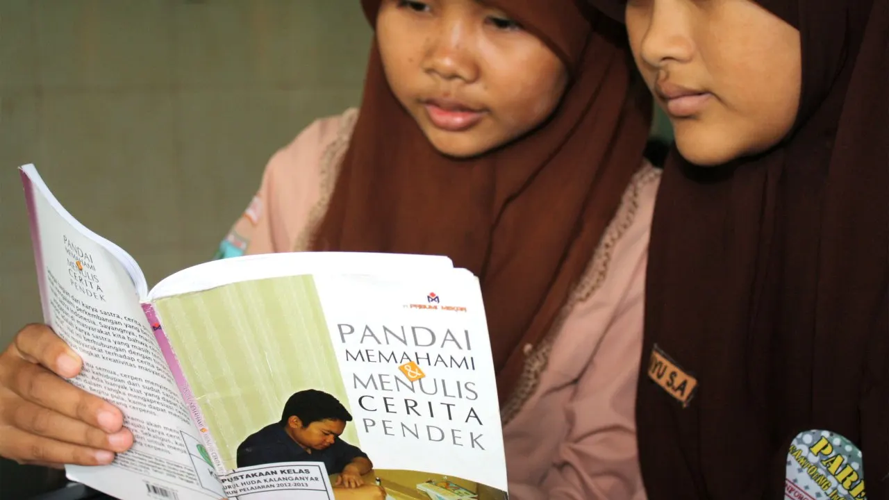 Dua siswi SMP membaca buku pemahaman sastra dan cerita pendek Bahasa Indonesia di perpustakaan sekolah